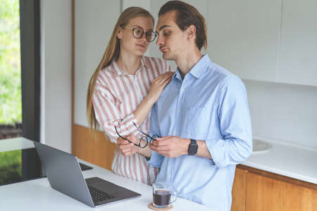 Young couple standing on the kitchen with laptop and working from home