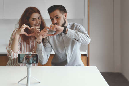 Front view of family couple making video at smartphone and tripod
