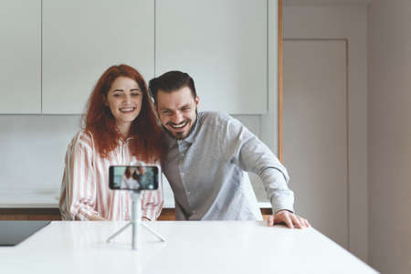 Front view of family couple talking with friends online at smartphone and tripodの写真素材