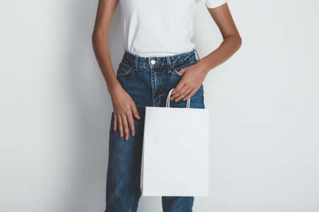 Girl wearing blank white t-shirt and holding white package bagの写真素材