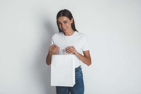 Woman wearing stylish green khaki t-shirt and holding blank white shopping bagの写真素材