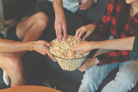 Cropped image of female and male hands taking popcorn from bowlの写真素材