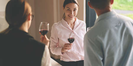 Front view of successful business woman smiling and holding red wineの写真素材