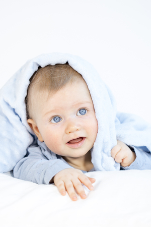 beautiful baby boy lying in bed on white backgroundの写真素材