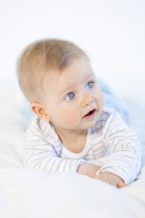 beautiful baby boy lying in bed on white backgroundの写真素材