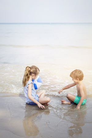 girl and boy playing water ball on the beachの写真素材