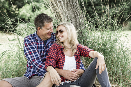 young laughing woman with his happy boyfriend sitting on the meadowの写真素材
