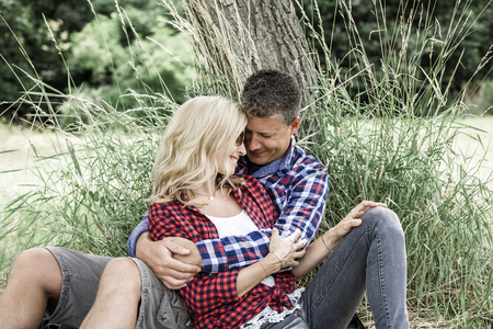 young laughing woman with his happy boyfriend sitting on the meadowの写真素材