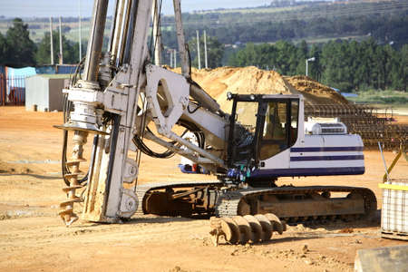 Large hole digger drilling on a construction site creating foundations for a building