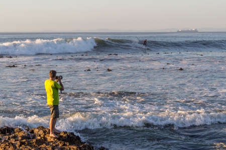 Photographer photographing surfer outdoors, sunny late afternoon