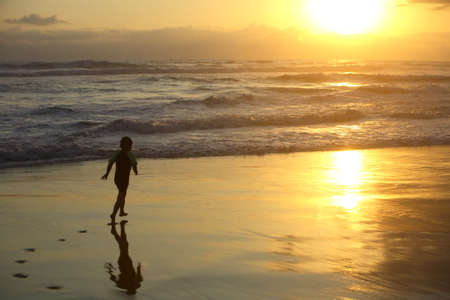 Boy running on the beach at sunsetの写真素材
