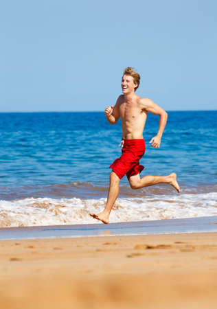 Physically fit man running on Beachの写真素材