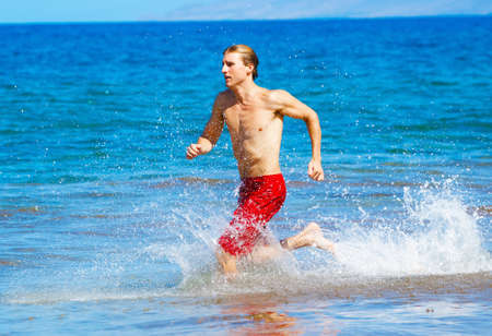 Physically fit man running on Beachの写真素材