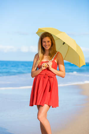 Beautiful Young Woman Walking on Tropical Beach with Colorful Umbrellaの写真素材