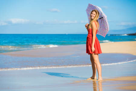 Beautiful Young Woman Walking on Tropical Beach with Colorful Umbrellaの写真素材