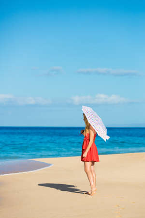 Beautiful Young Woman Walking on Tropical Beach with Colorful Umbrellaの写真素材
