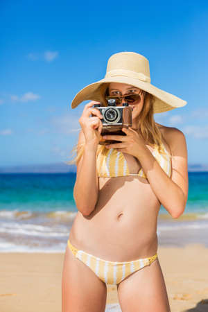 Beautiful Young Woman at the Beach with Vintage Cameraの写真素材