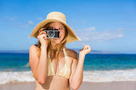 Beautiful Young Woman at the Beach with Vintage Cameraの写真素材
