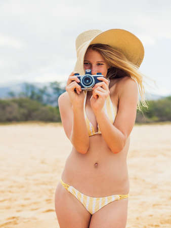 Beautiful Young Woman at the Beach with Vintage Cameraの写真素材