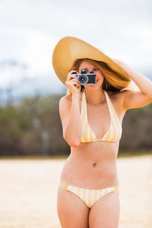 Beautiful Young Woman at the Beach with Vintage Cameraの写真素材