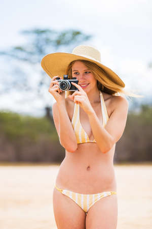 Beautiful Young Woman at the Beach with Vintage Cameraの写真素材