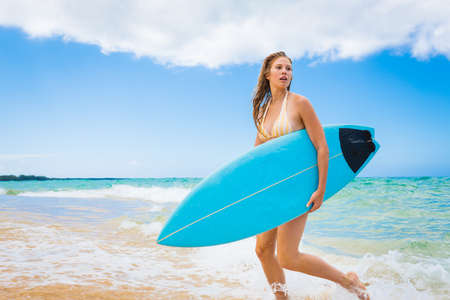 Beautiful Young Woman Surfer Girl in Bikini with Surfboard at a Beachの写真素材