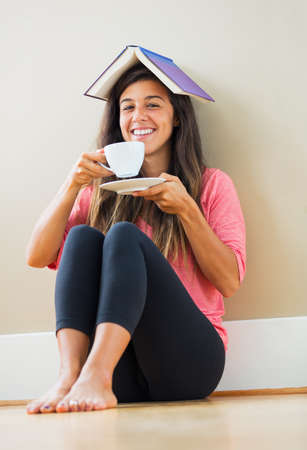 beautiful happy young woman drinking tea at home in living roomの写真素材