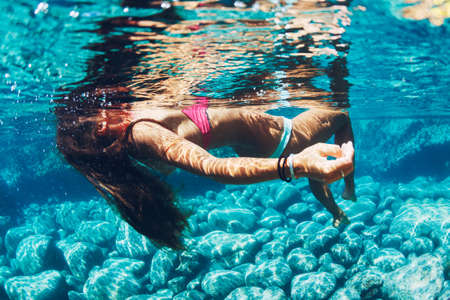 Attractive young woman floating in beautiful ethereal natural ocean pool, Underwater View