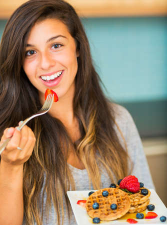 Woman Eating Waffles with Fresh Fruit for Breakfastの写真素材