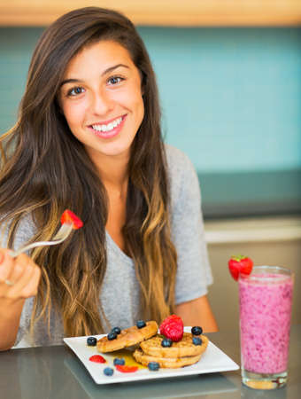 Woman Eating Waffles with Fresh Fruit for Breakfastの写真素材