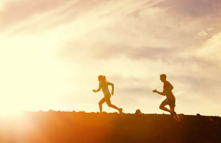 Silhouette of man and woman running jogging together into sunset, Wellness fitness concept