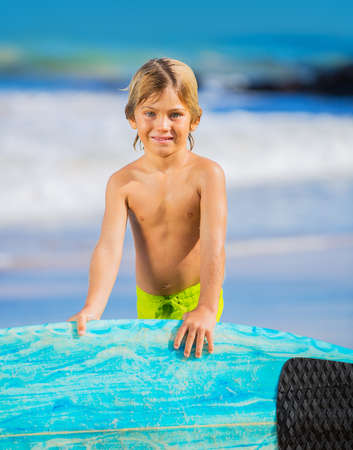 Young surfer, happy young boy at the beach with surfboard