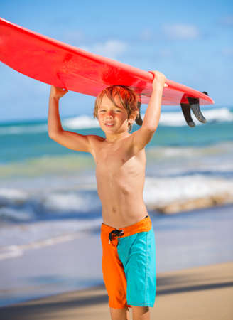 Young surfer, happy young boy at the beach with surfboardの写真素材