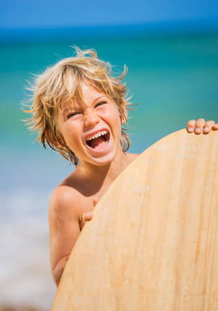 Happy Young boy having fun at the beach on vacation, with skimboardの写真素材