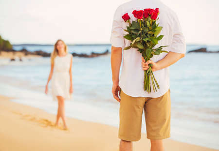Young Couple in Love, Man holding surprise bouquet of roses for beautiful young woman, Romantic Dateの写真素材