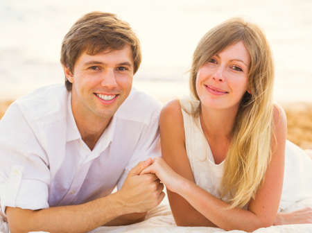 Young couple in love, Man and woman enjoying romantic sunset at the beachの写真素材