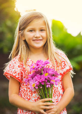 Portrait of a smiling cute little girl with flowersの写真素材