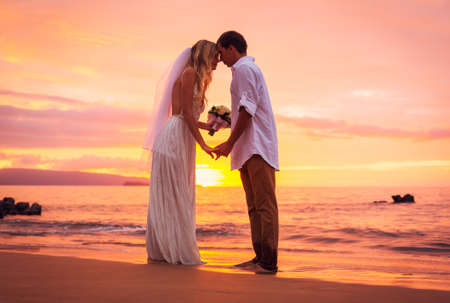 Bride and Groom, Enjoying Amazing Sunset on a Beautiful Tropical Beach, Romantic Married Couple Holding Handsの写真素材