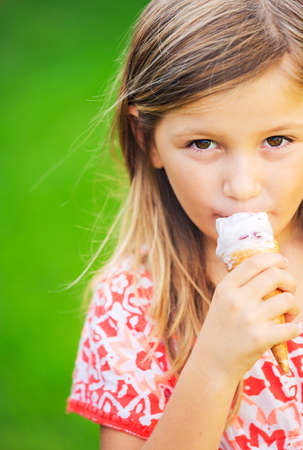 Happy cute little girl eating ice cream coneの写真素材