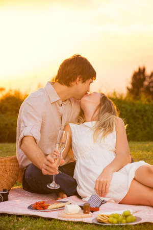 Attractive couple kissing on romantic sunset picnicの写真素材