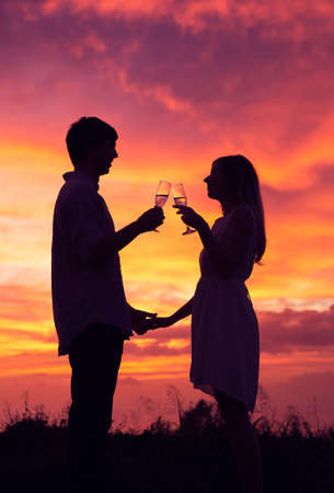 Silhouette of couple drinking champagne at sunset 