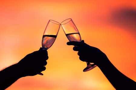 Silhouette of couple drinking champagne at sunset の写真素材