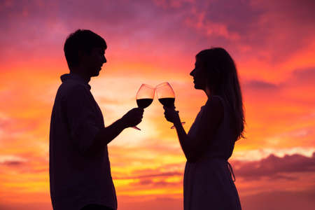 Silhouette of couple drinking wine at sunsetの写真素材