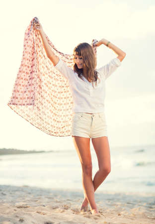 Beautiful young woman on the beach at sunset, Fashion lifestyle warm backlit sunlightの写真素材