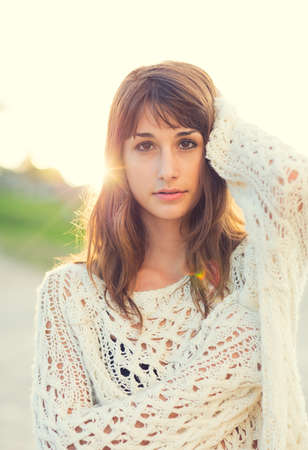Beautiful young woman in sweater on the beach at sunset, Fashion lifestyle warm backlit sunlightの写真素材