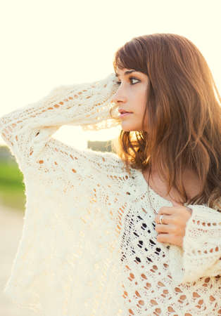 Beautiful young woman in sweater on the beach at sunset, Fashion lifestyle warm backlit sunlightの写真素材