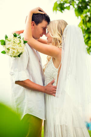 A married couple, bride and groom, at sunset on a beautiful tropical beachの写真素材