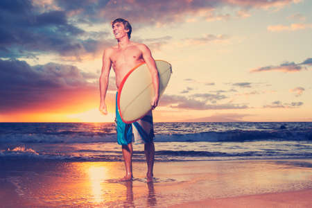 Surfer on the beach at sunset in Hawaii