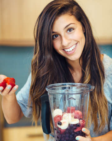 Beautiful Young Woman Making Fruit smoothieの写真素材