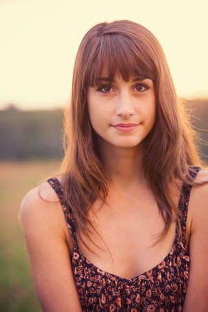 Beautiful woman in golden field at sunset, Fashion lifestyle, Vibrant color, Backlit warm tonesの写真素材